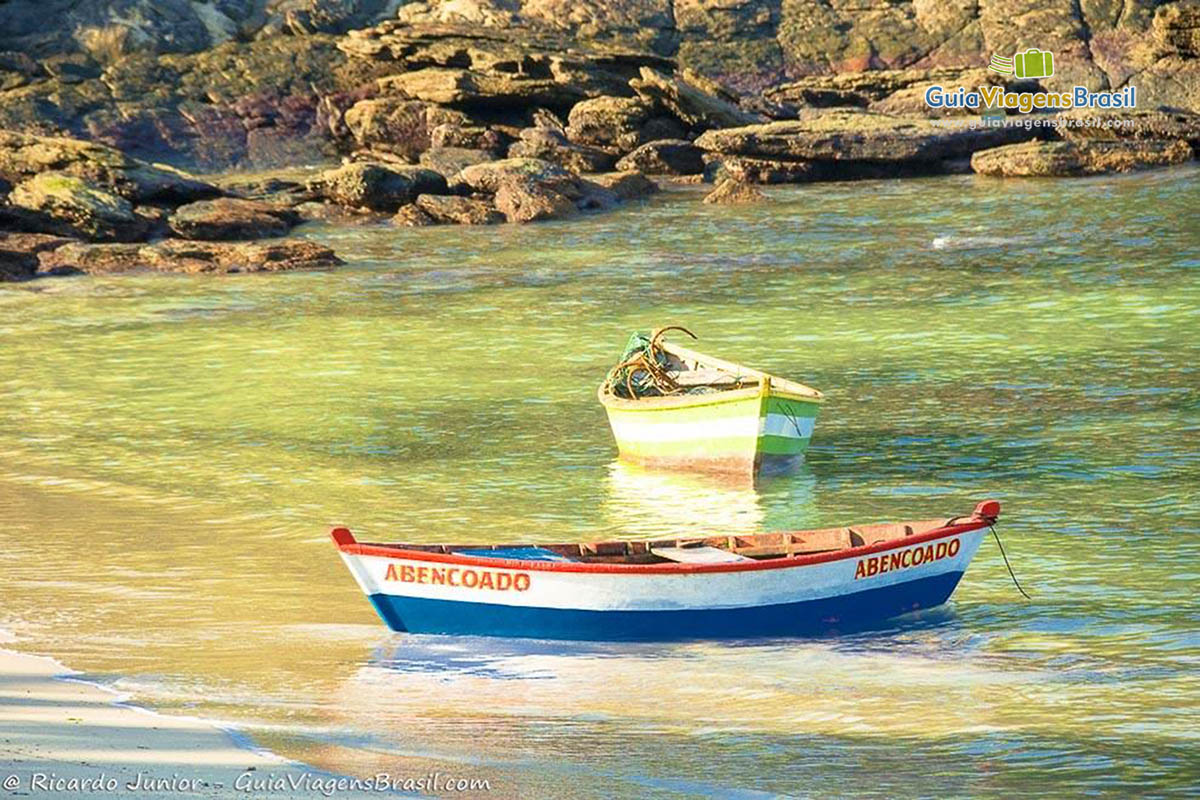 Imagem de dois barcos na beira do mar, na Praia do Forno.