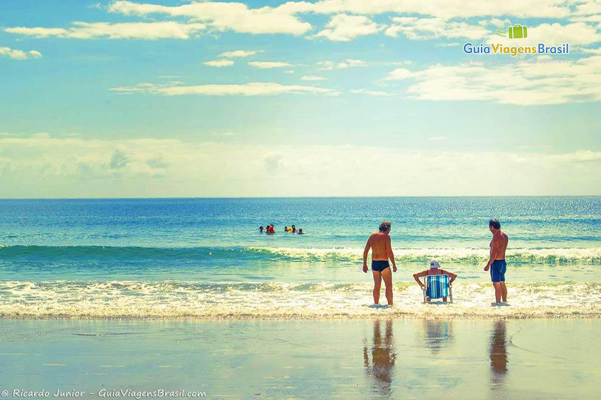 Imagem de três pessoas na beira da Praia Bombas.