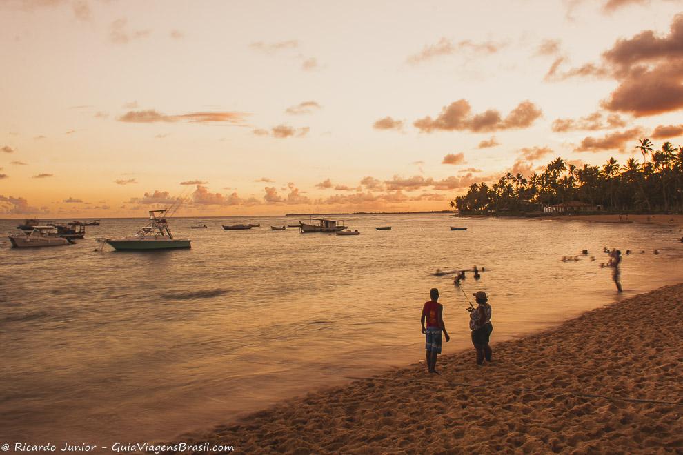 Lanchas ancoradas, pescadores e turistas apreciando o por do sol na Praia do Forte, Bahia. Photograph by Ricardo Junior / www.ricardojuniorfotografias.com.br