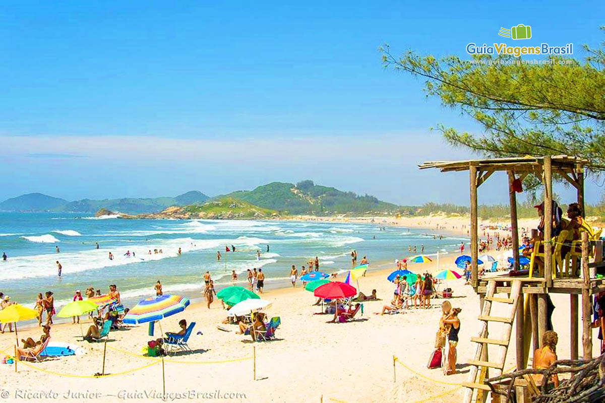 Foto orla e turistas na Praia da Ferrugem, Garopaba, SC.