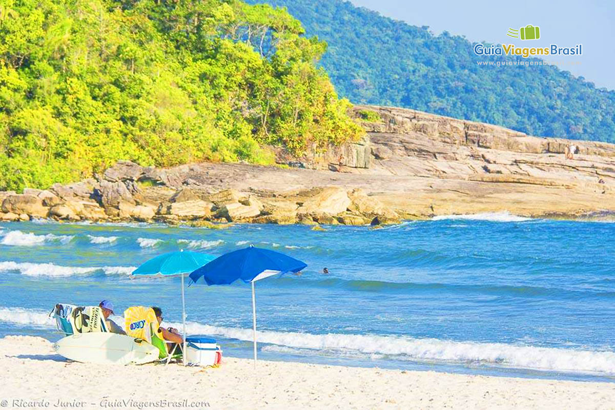 Foto guarda sol e costão rochoso na Praia de Cambury, São Sebastião, SP.