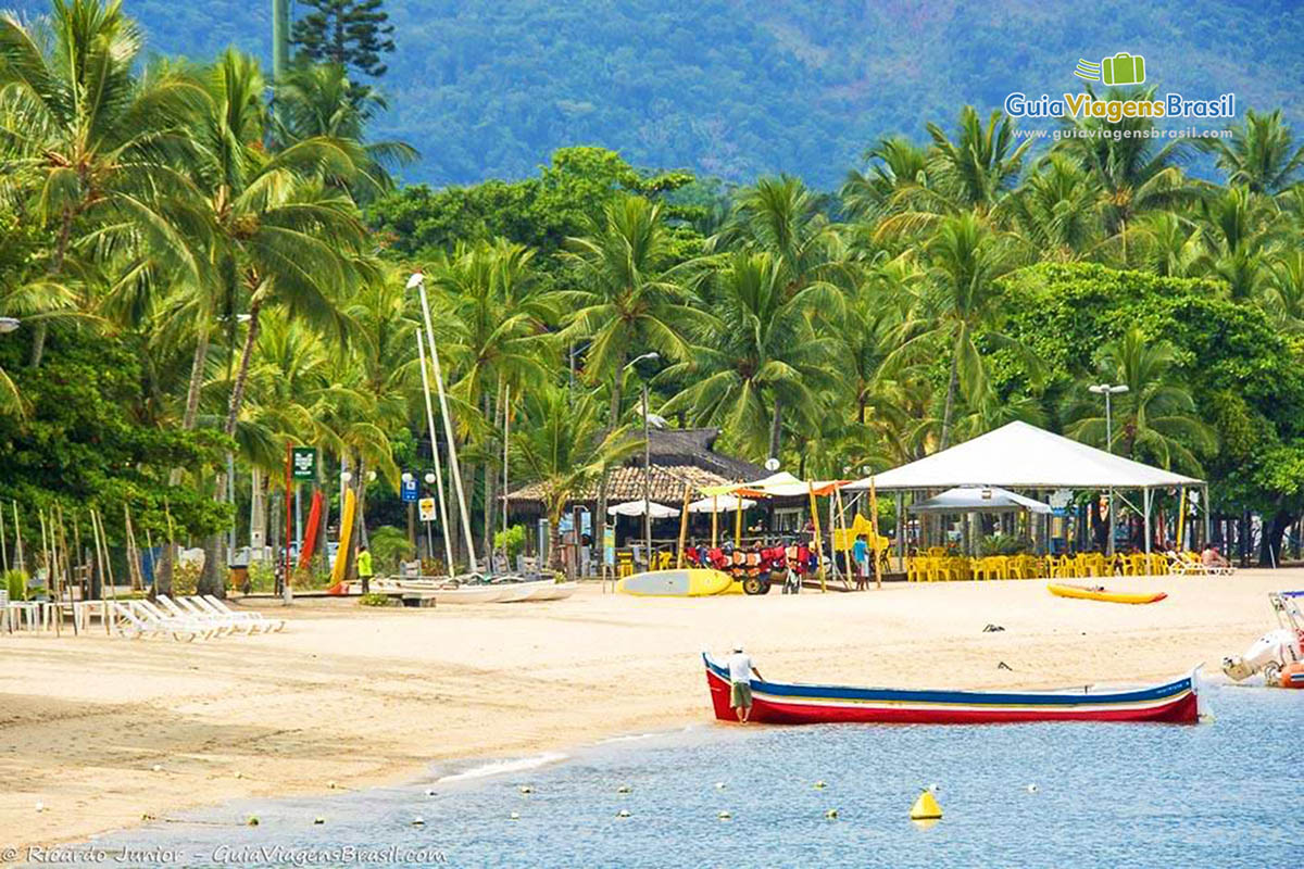 Foto da orla com barco na Praia de Perequê, em Ilhabela, SP.