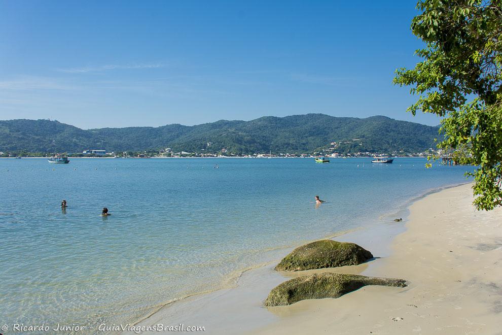 Imagem de três pessoas nas águas calmas da Ilha Porto Belo.