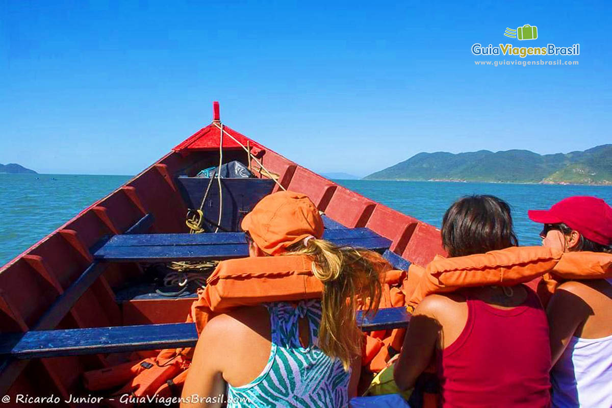 Imagem de amigas no barco com coletes salva vidas.