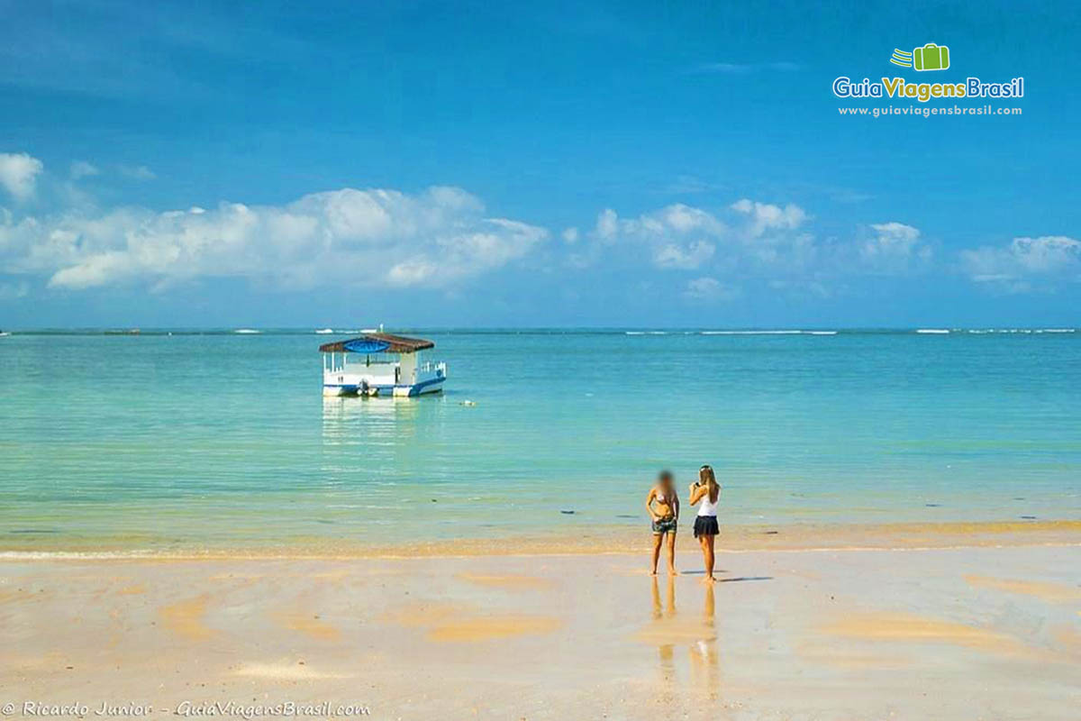 Imagem de amigas tirando foto na beira da Praia Ponta Verde.