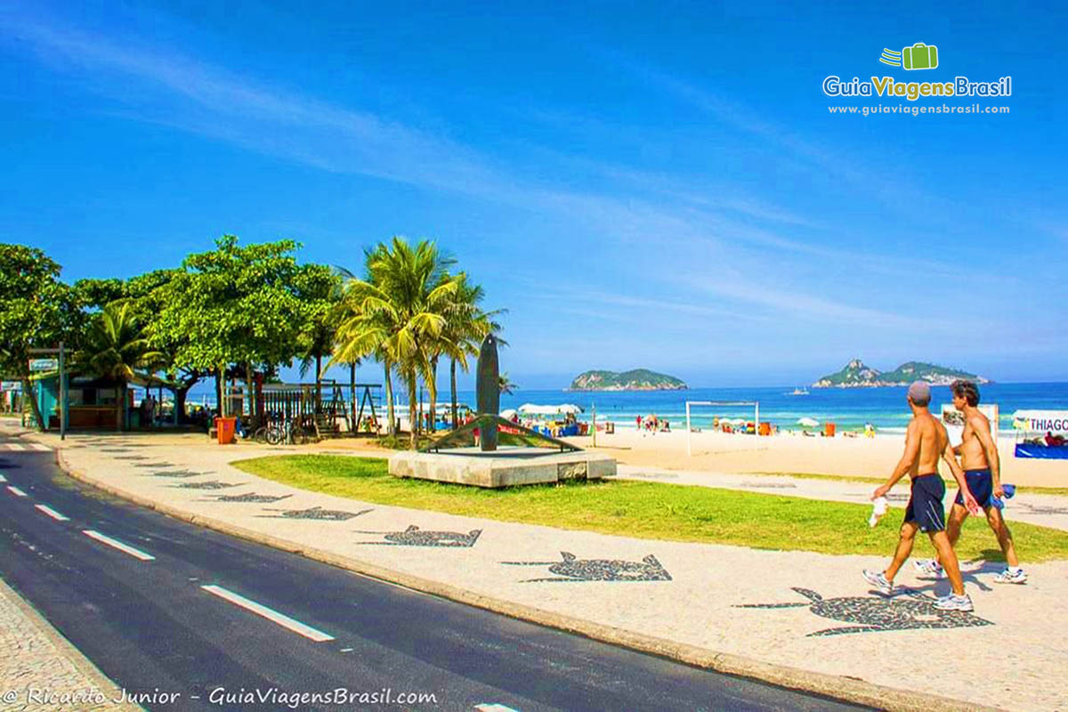 Imagem de amigos andando no calçadão da praia.