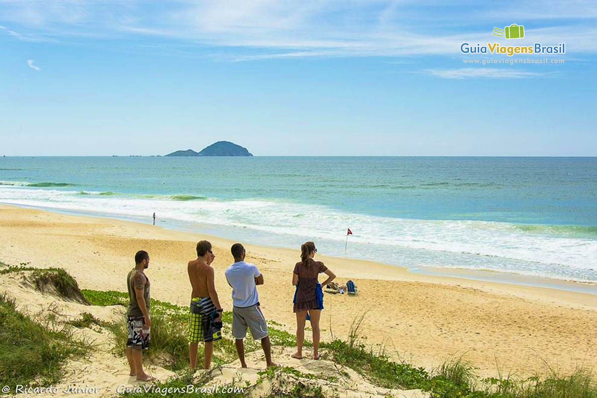 Imagem de amigos chegando na Praia Moçambique e estão olhando para mar.