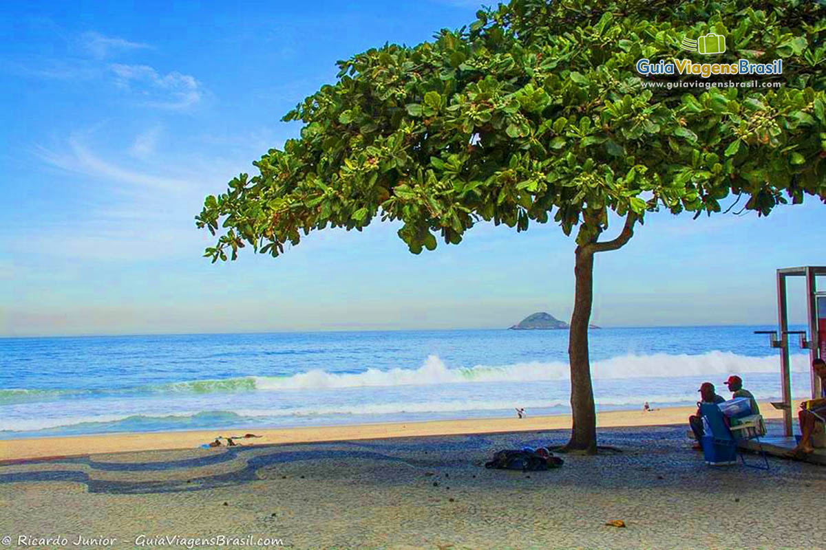 Imagem de amigos sentados na orla da Praia São Conrado