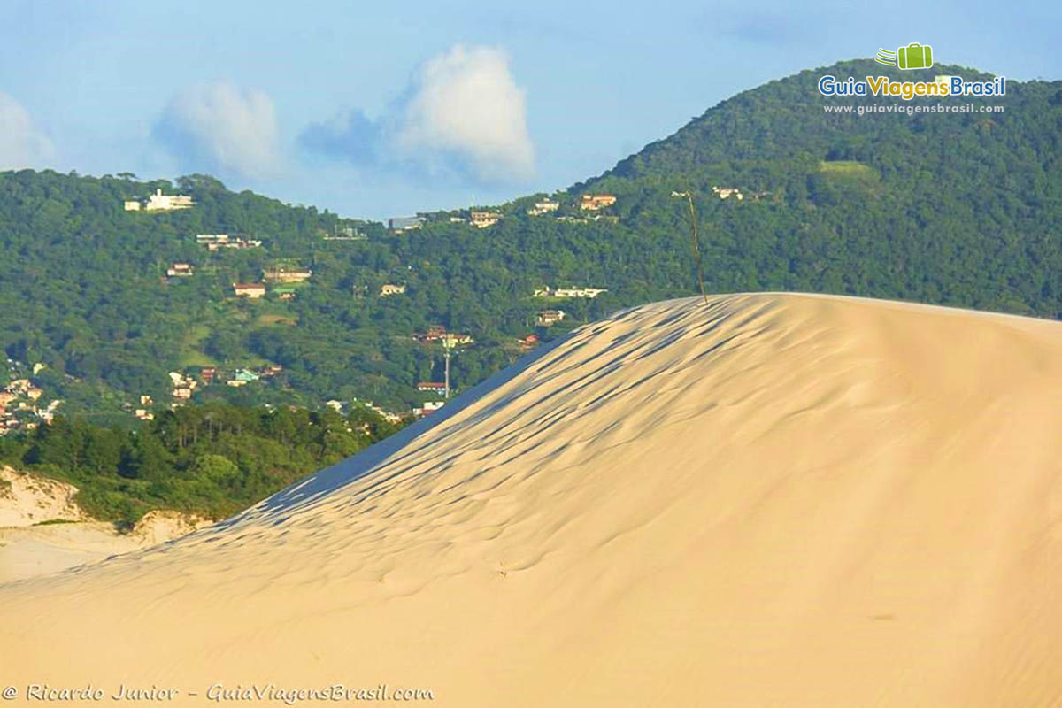 Imagem das dunas a ao fundo morro com vegetação verdinha.