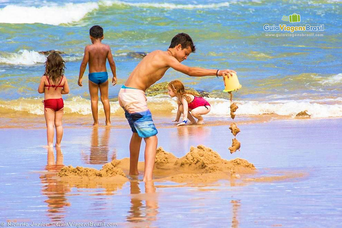 Imagem de crianças brincando na beira da praia.