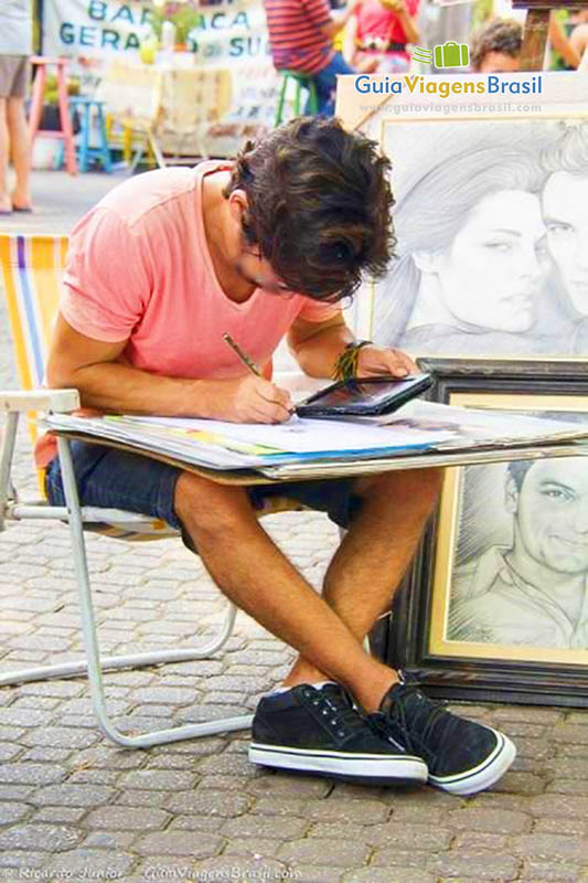 Imagem de artista desenhando rosto das pessoas. 