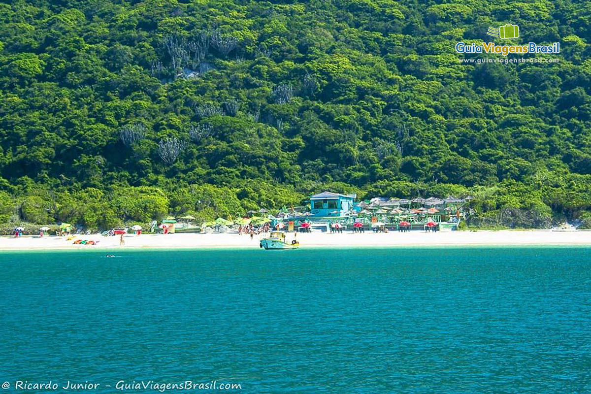 Imagem do mar e ao fundo o bar que possui na Praia do Forno.