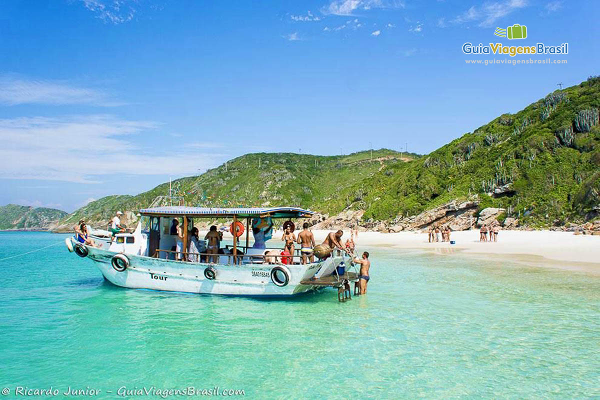 Imagem de barco chegando com turistas na praia.