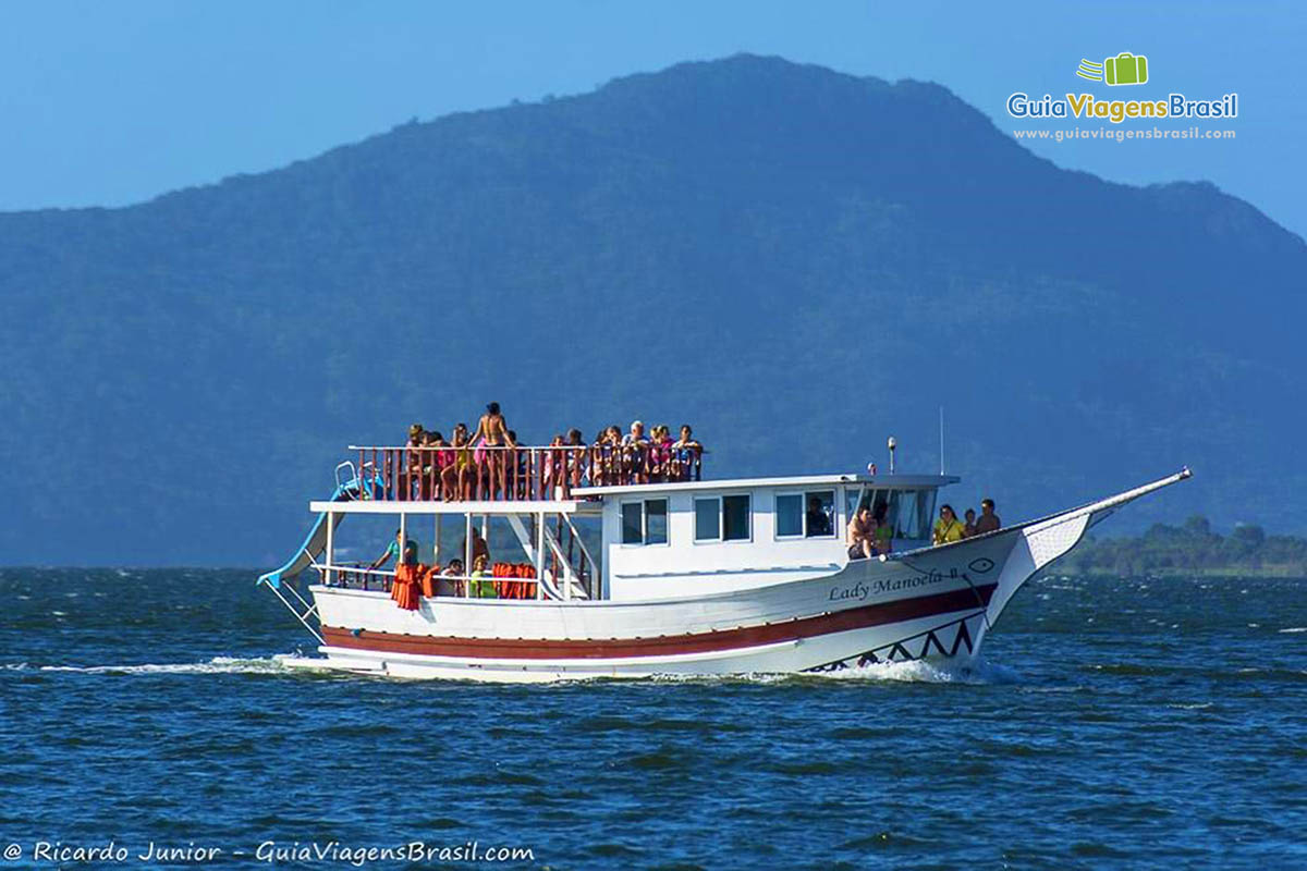 Imagem de barco de passeio, repleto de turistas.