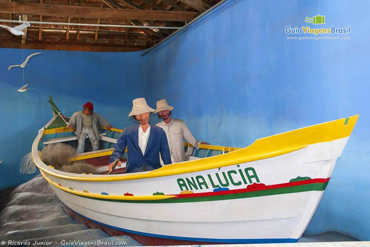 Imagem de um barco de pescador com réplica de pescadores dentro do barco.