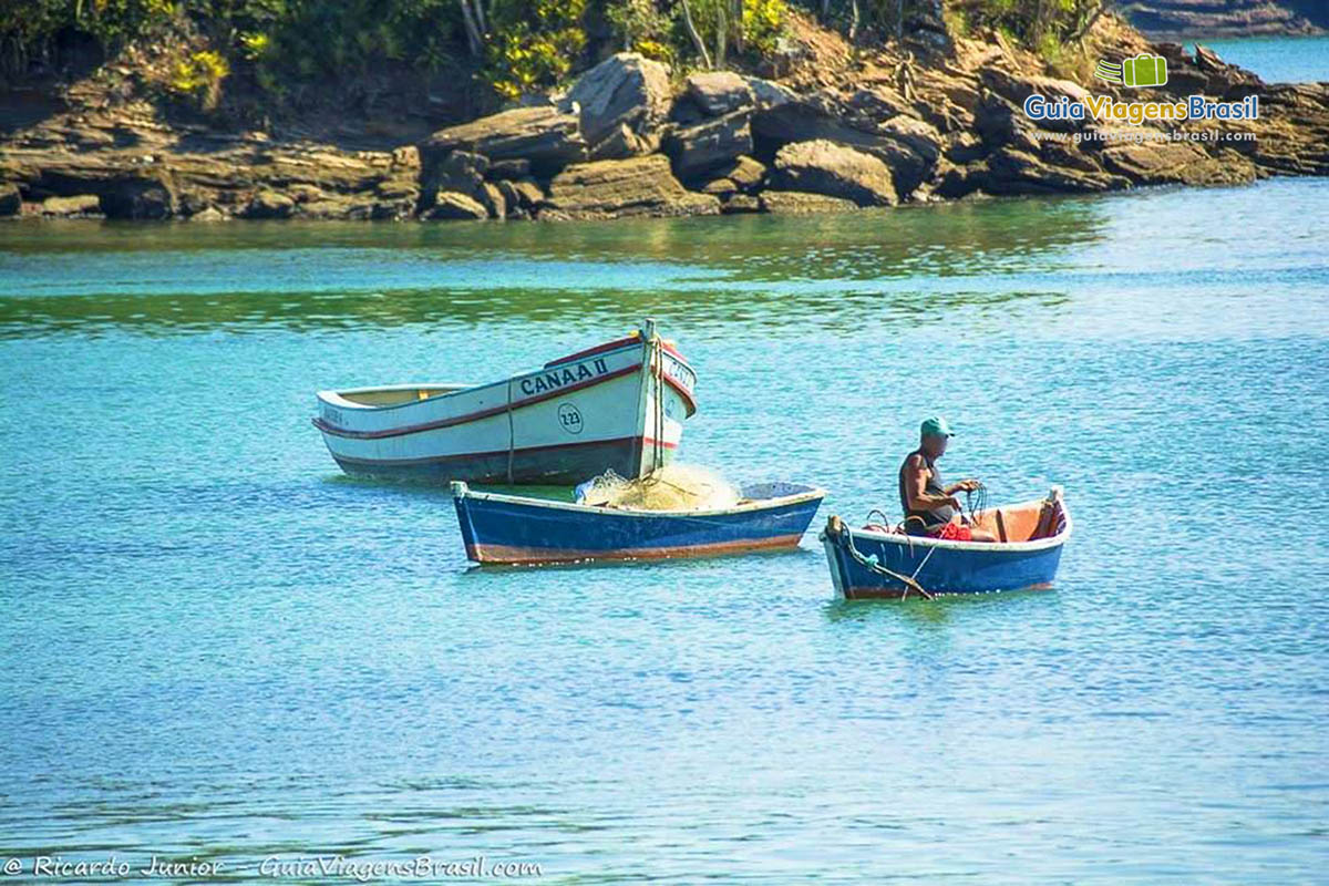 Imagem de um pescador com seu barco no mar da Praia da Armação.