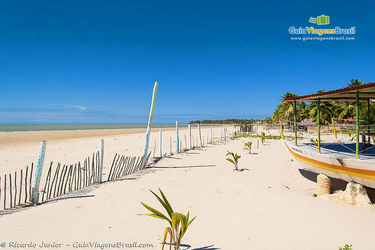 Imagem de barco parado nas areia da praia.