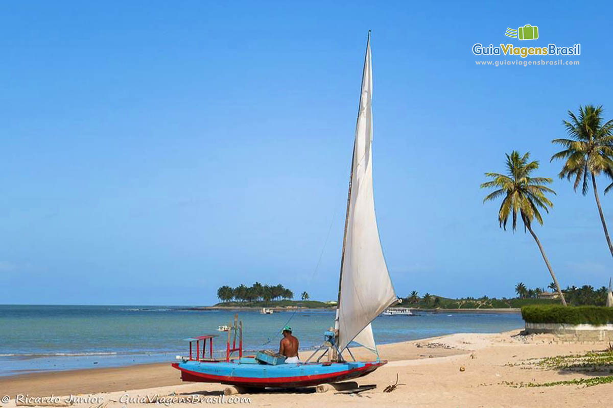 Imagem de barco a vela nas areia da Praia Maracajaú.