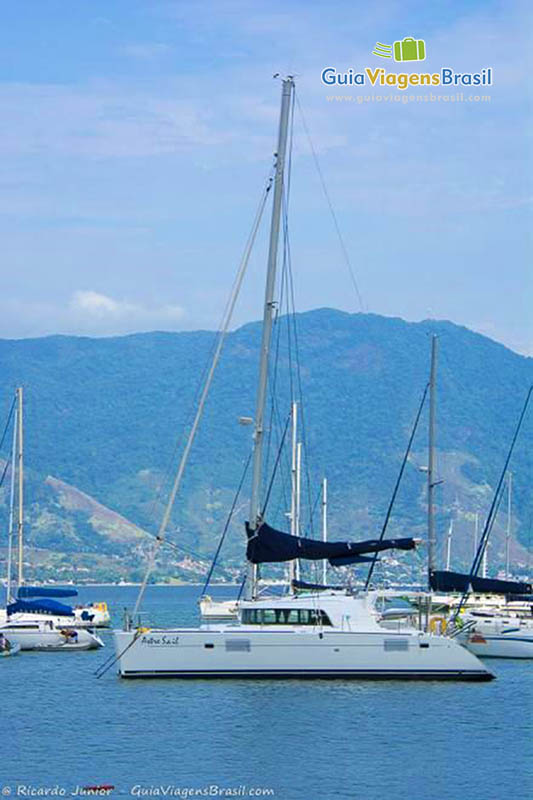 Imagem de um barco com velas pretas no mar em Ilhabela.