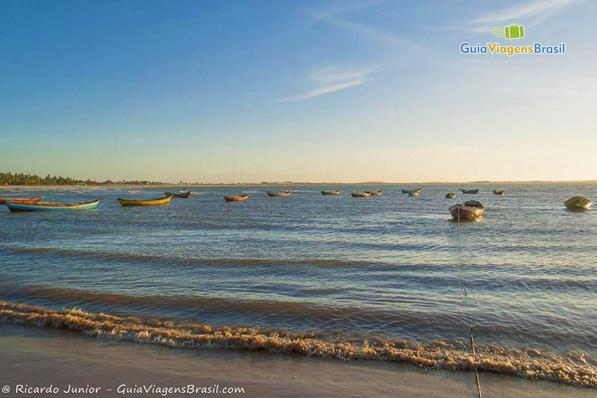 Imagem do final da tarde com vários barcos de pescadores parados no mar.