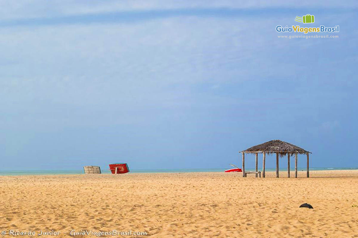 Imagem de barracas de sapê na praia.