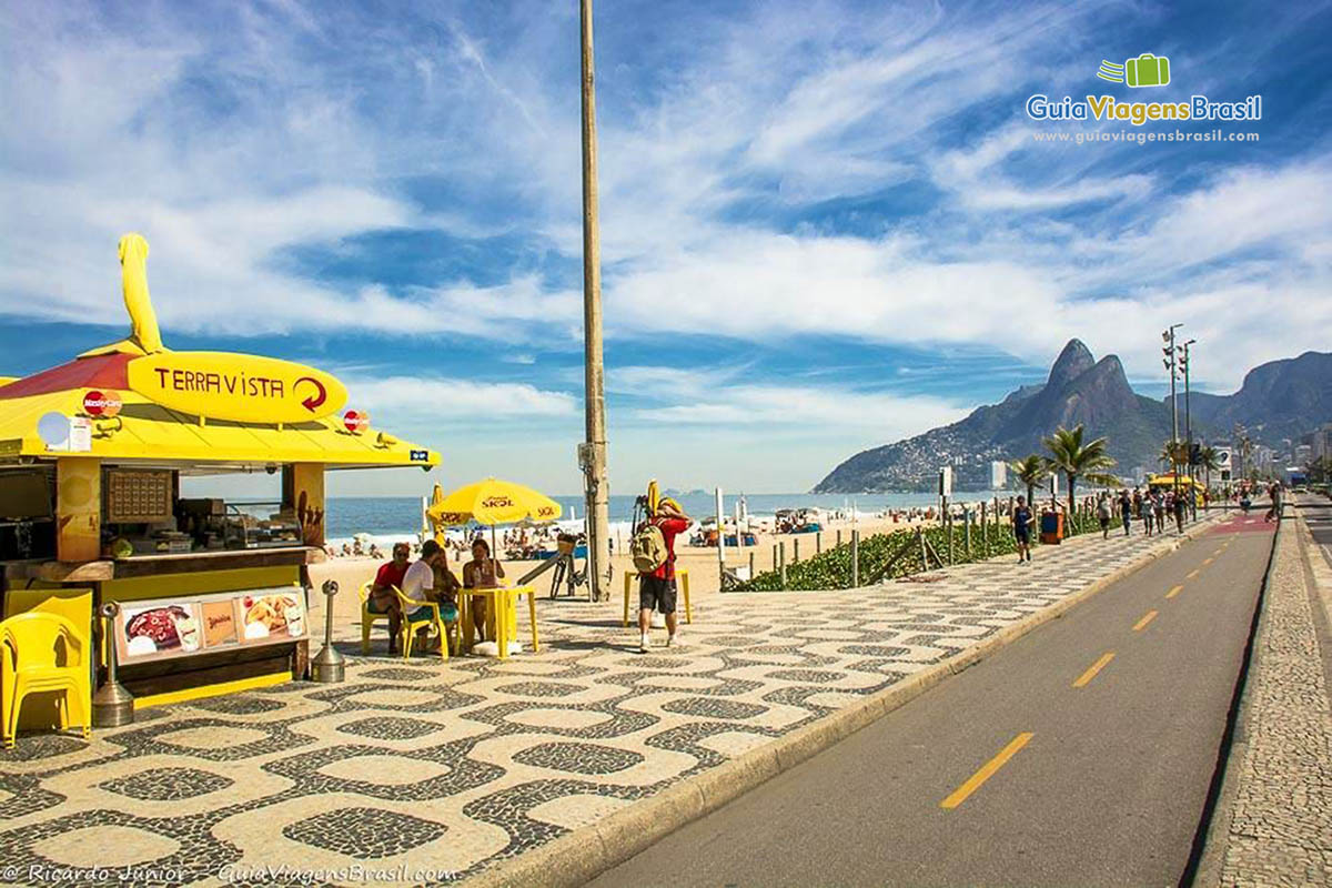 Imagem de um quiosque amarelo no calçadão da praia.