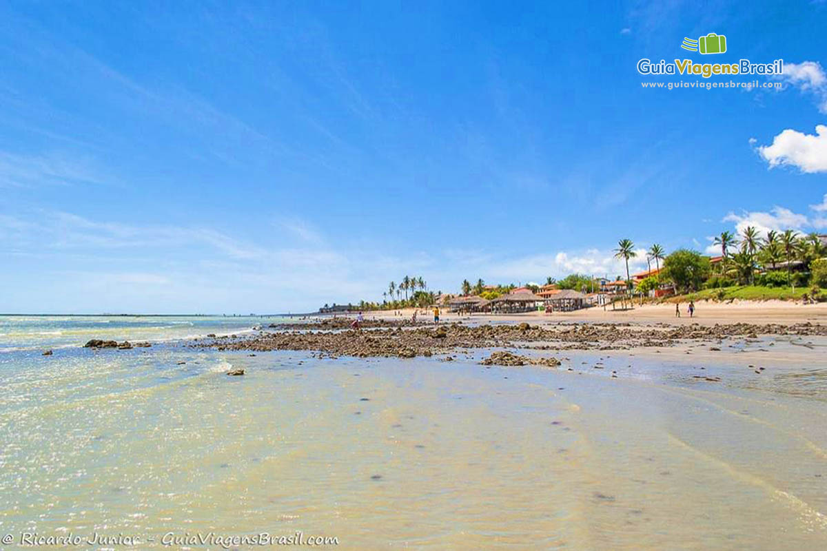 Imagem do trecho que possui algumas pedras na beira da praia.