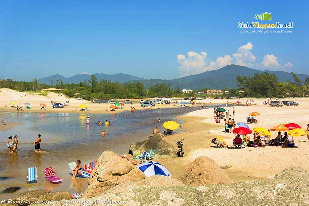 Imagem de famílias aproveitando um belo dia de sol na lagoa.