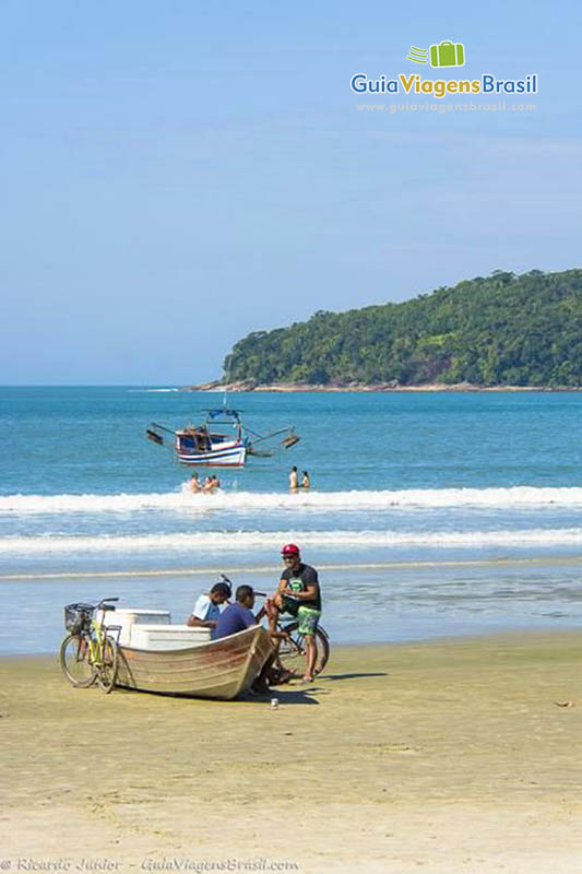 Imagem de uma bicicleta encostada em um barco nas areias da Praia Maranduba.