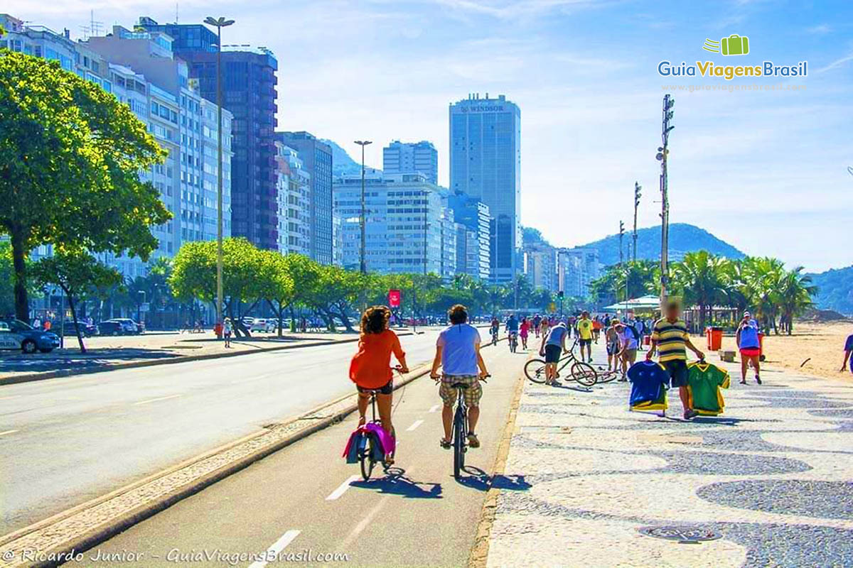 Imagem de pessoas andando de bicicletas na orla da praia.