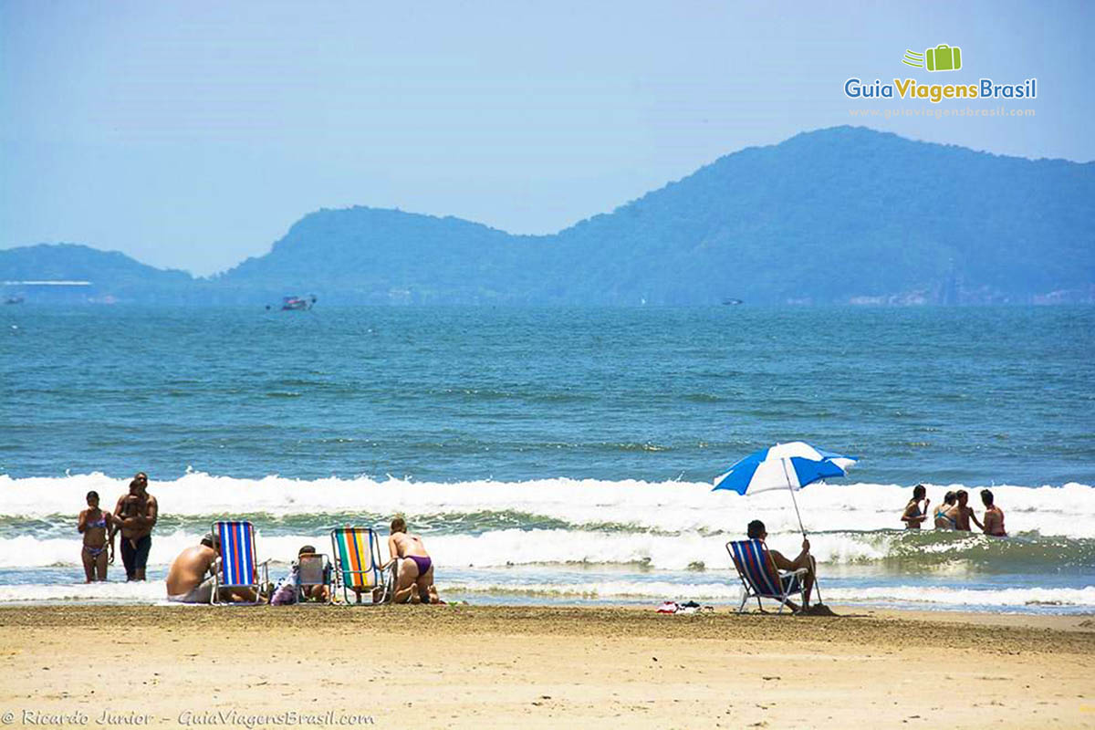 Imagem de família brincando na areia na beira da praia.