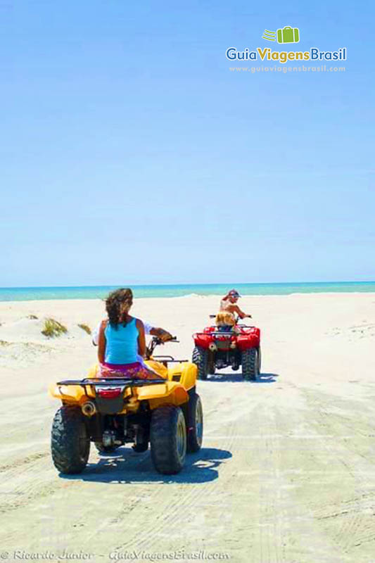 Imagem de duas amiga andando de bugue nas areias da praia.