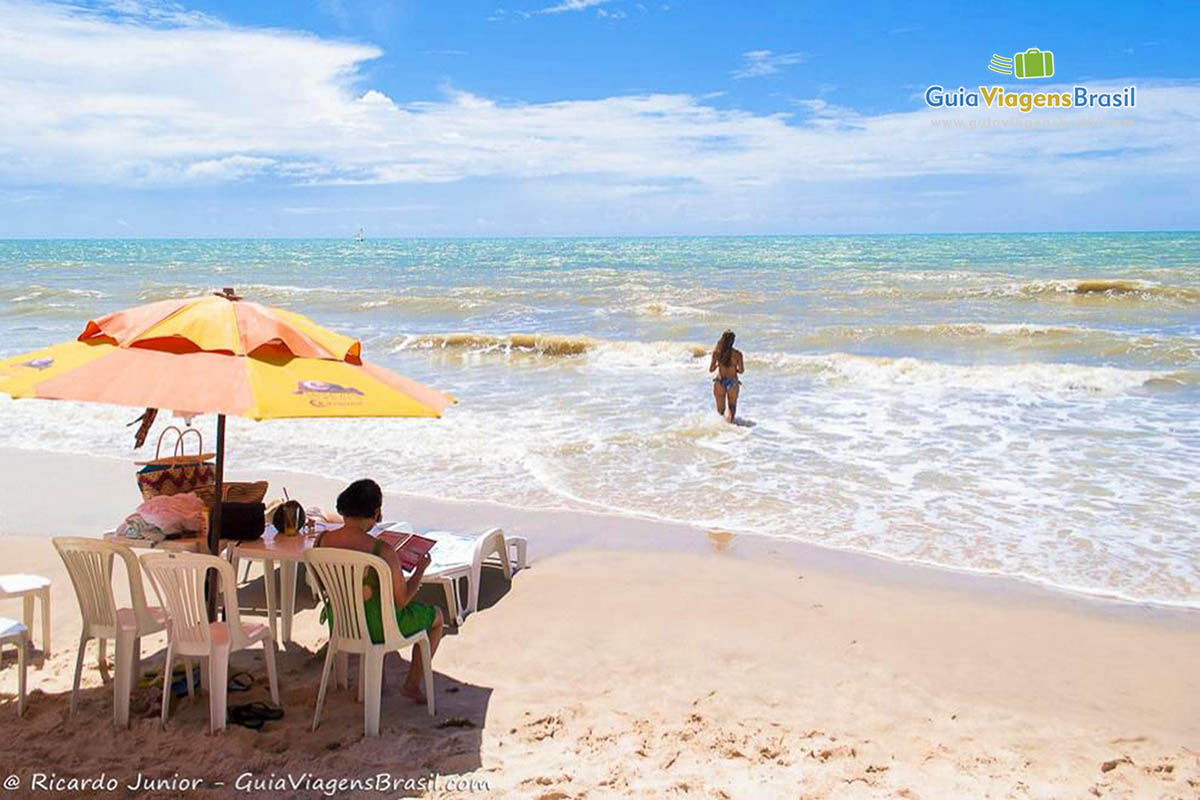Imagem de cadeiras e mesas nas areias da Praia Canoa Quebrada para turistas.
