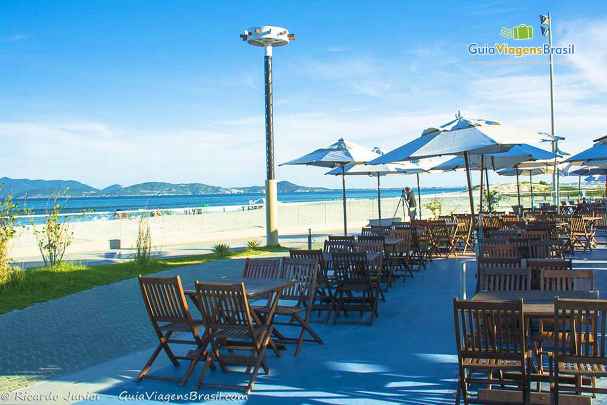 Imagem de cadeiras de madeira com guarda sol no belo calçadão da Praia do Forte.