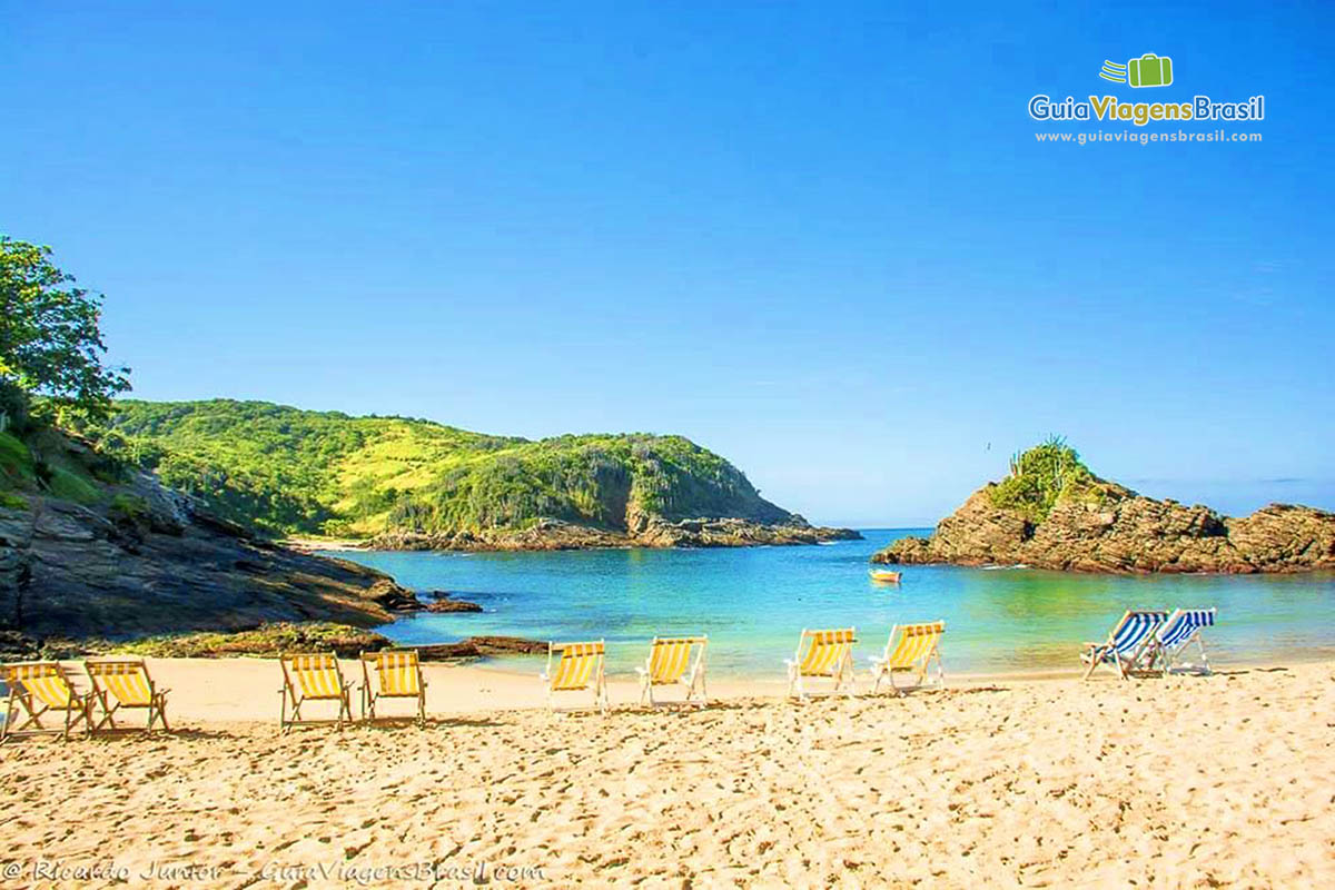 Imagem de cadeiras de praia lado a lado na areia da praia.