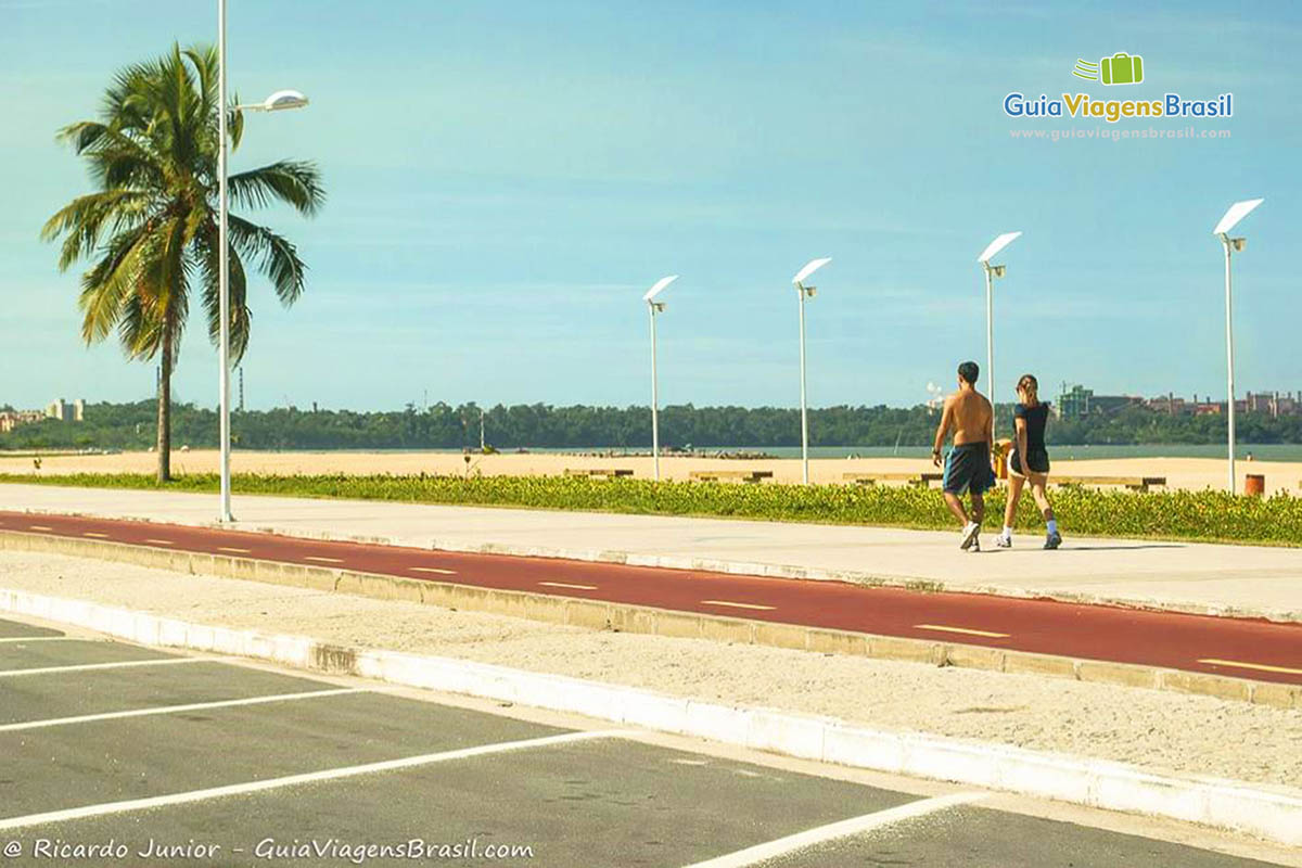 Imagem de casal caminhando no calçadão da Praia de Cambori.