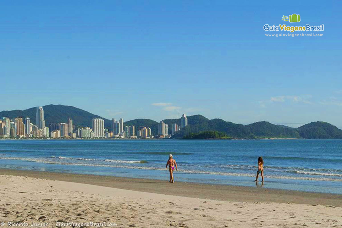 Imagem de duas pessoas caminhando na Praia Central.