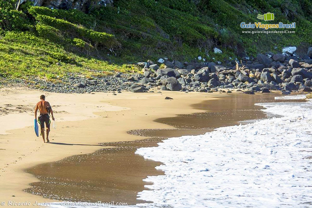 Imagem de um surfista caminhando as areias da Praia de José Gonçalves.