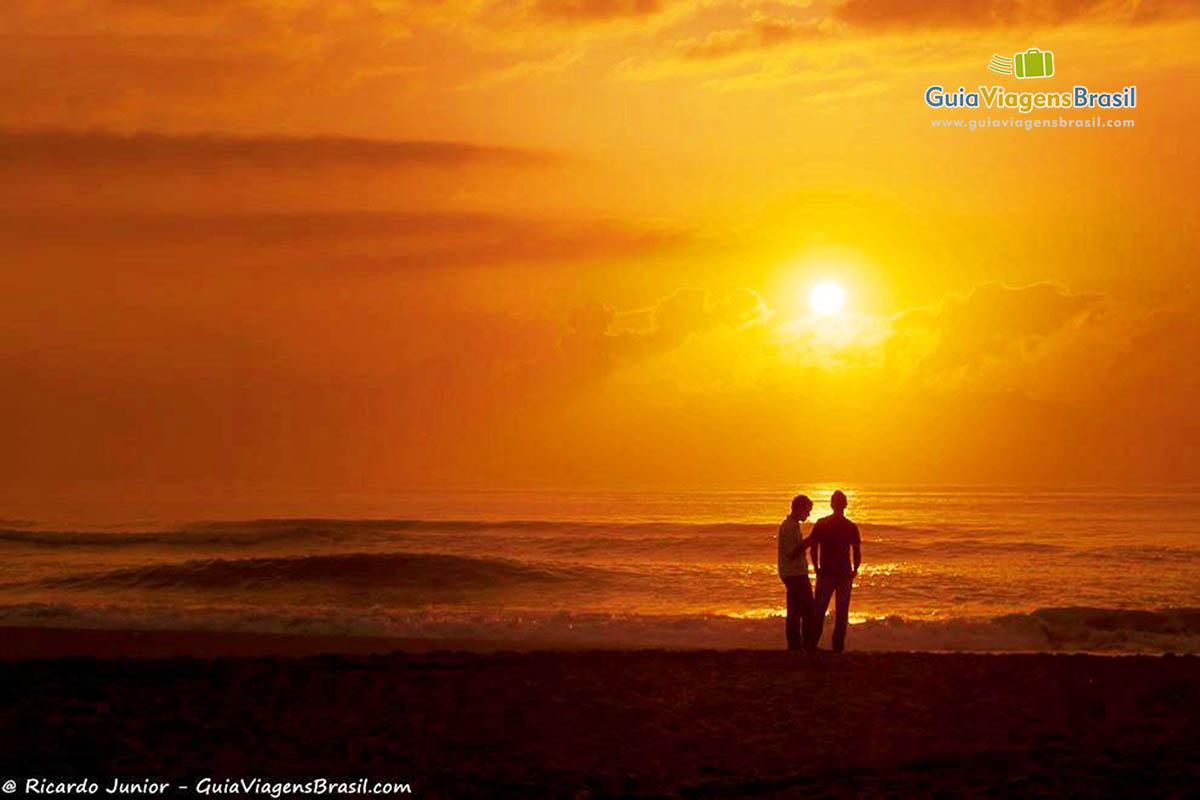 Imagem de casal admirando as belezas do por do sol.