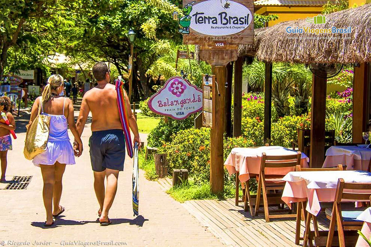 Imagem de casal andando na Praia do Forte.