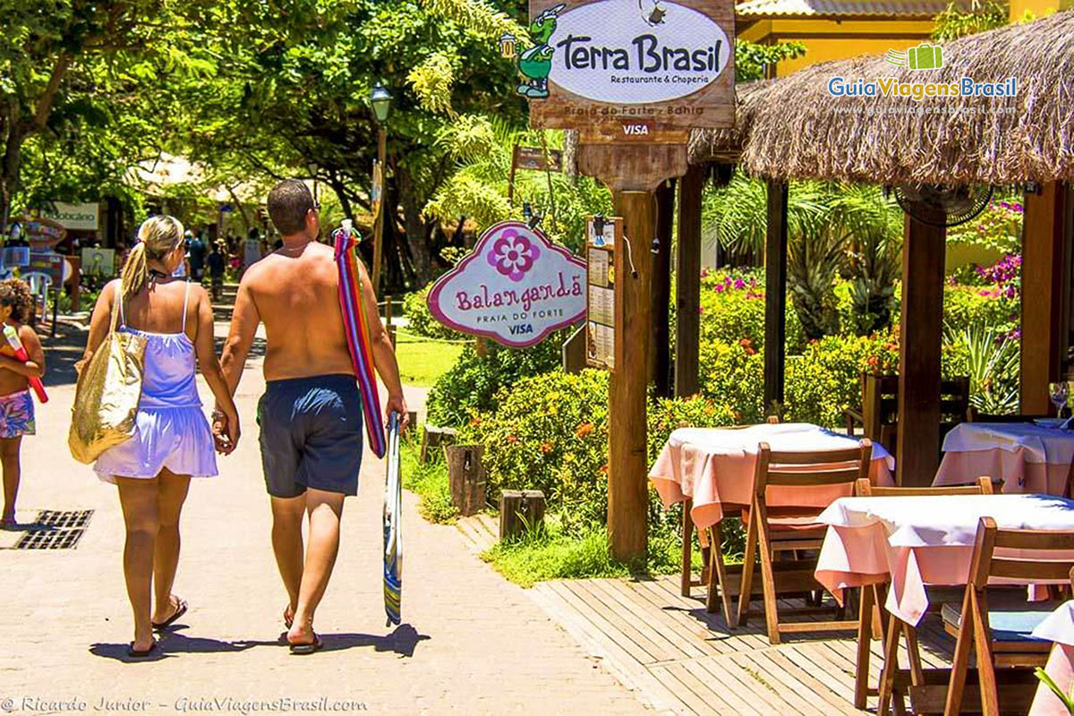 Imagem de casal andando na Praia do Forte.