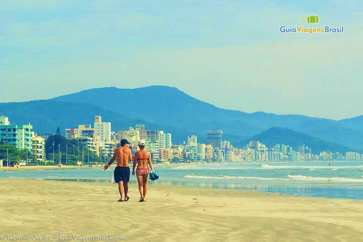 Imagem de casal caminhando na beira da praia.