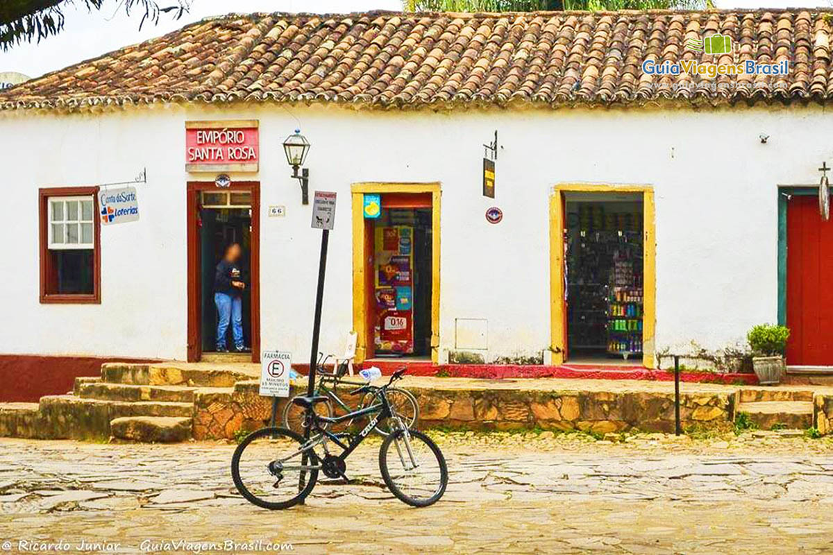 Imagem de uma bicicleta encostada em um poste e ao fundo um empório.