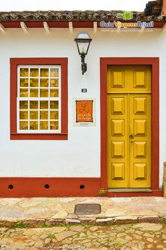 Imagem da fachada de uma pousada com porta em madeira trabalhada.