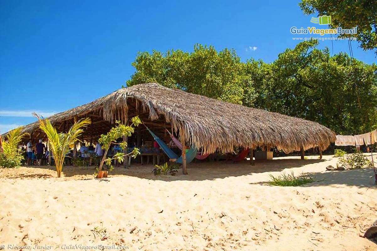 Imagem de uma enorme tenda de sapê onde turistas comem e descansam durante o lindo passeio.