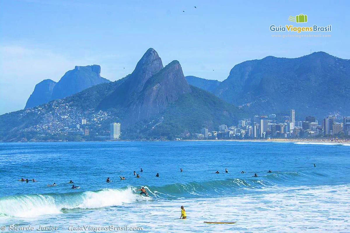 Imagem de vários surfistas no mar azul Arpoador.