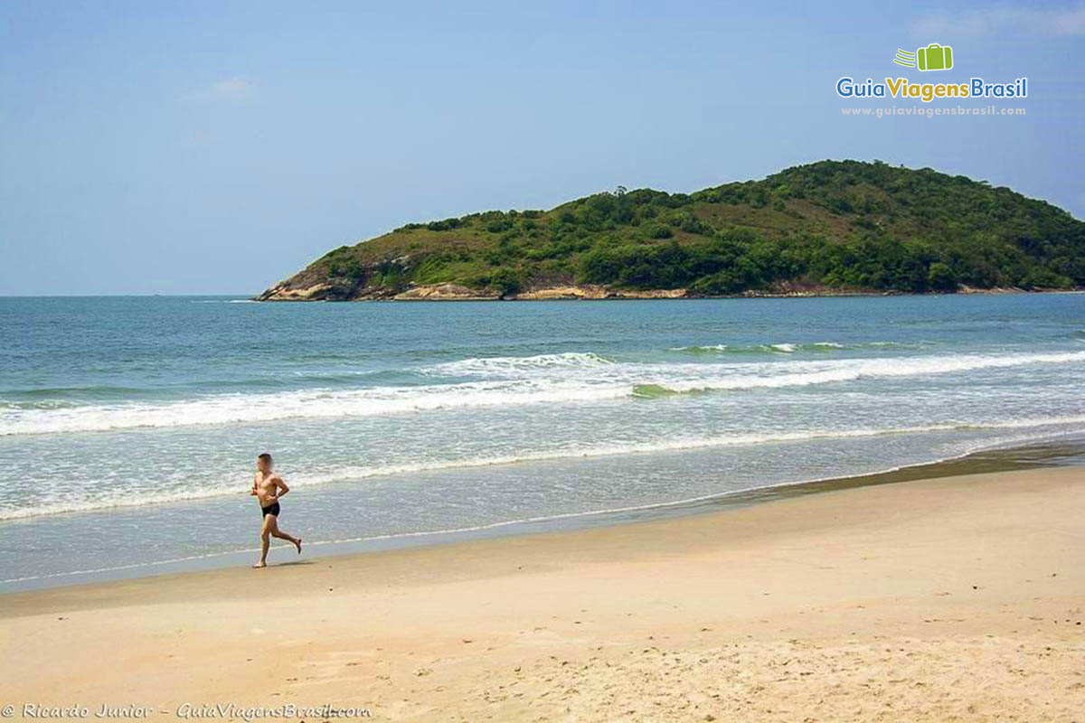 Imagem de uma pessoa correndo na beira da praia.
