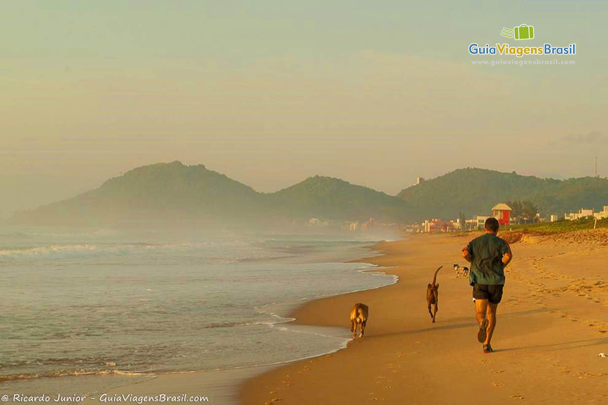 Imagem de uma pessoas correndo na beira da Praia dos Amores.