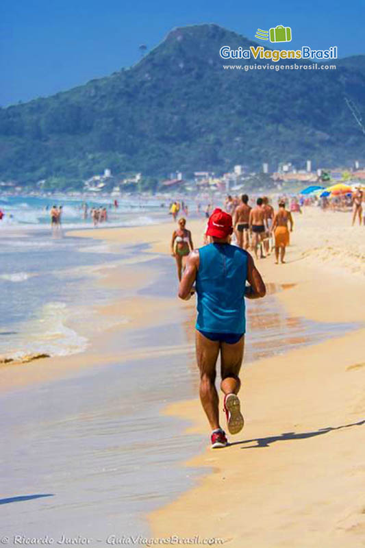 Imagem de um homem correndo nas areias da praia.
