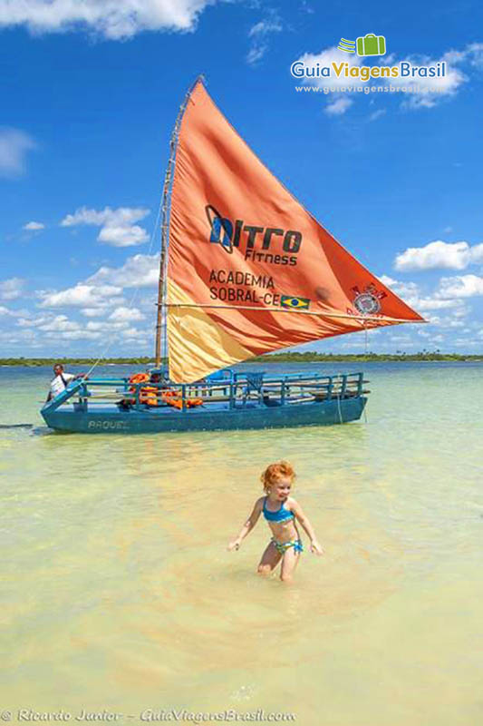 Imagem de uma criança brincando próximo a uma barco.